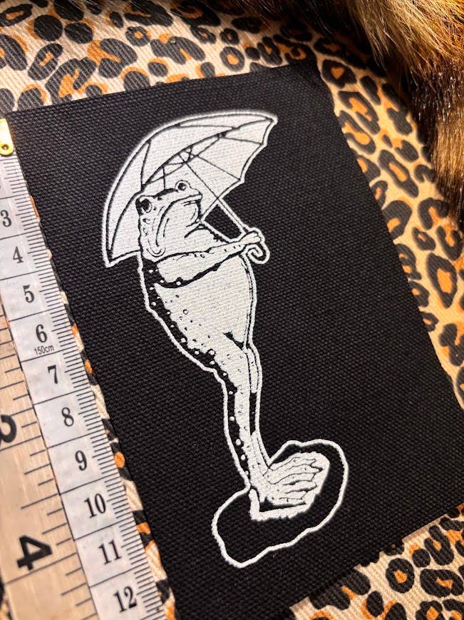 Sad frog holding an umbrella in the rain patch.