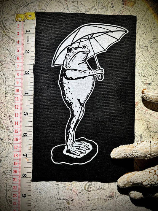 Sad frog holding an umbrella in the rain patch.