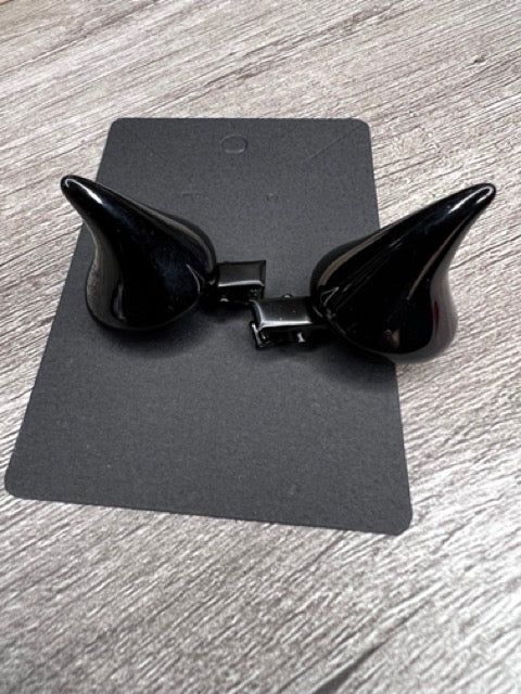 Close-up of black devil horn hair clips on a display card